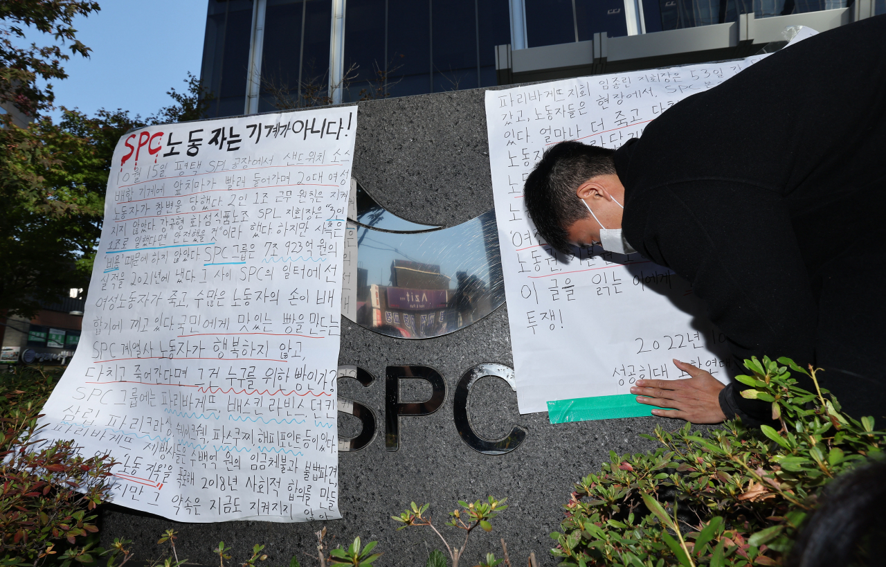 지난 20일 오후 서울 양재동 SPC 본사 앞에서 열린 평택 SPC 계열사 SPL의 제빵공장 사망 사고 희생자 서울 추모행사에서 성공회대 노학연대모임 가시 관계자가 대자보를 붙이고 있다. [연합]