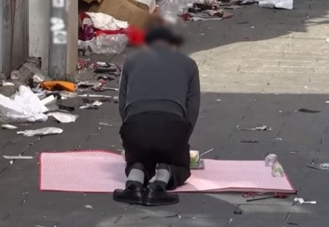 지난 29일 참사가 벌어진 서울 용산구 이태원동 현장에 제삿상을 차린 인근 상인 A 씨가 무릎을 꿇고 앉아 있다. [MBC PD수첩 방송 캡처]