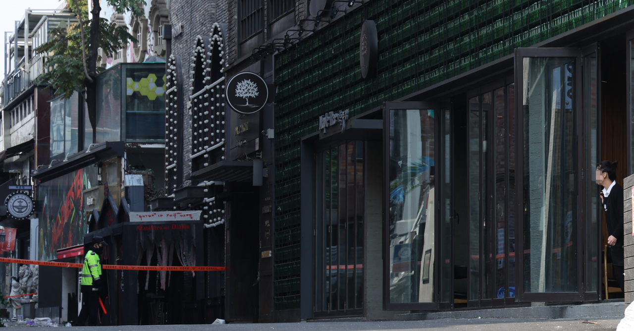 A shop owner looks on as a police officer patrols the site of the Itaewon crush surge on Monday. (Yonhap)