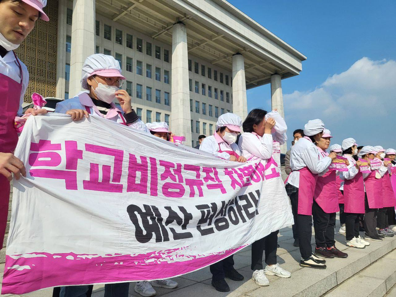 전국학교비정규직노동조합 급식실 조합원들이 지난 8일 서울 영등포구 국회 본관 계단에서 학교급식실 폐암 산재 대책 마련과 노동환경 개선 예산 편성을 요구하며 기자회견을 하고 있다. [연합]
