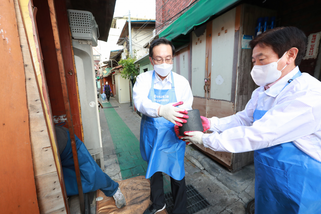 지난 14일 서울 영등포구 쪽방촌에서 손태승 우리금융그룹 회장과 임직원들이 연탄을 옮기고 있다.[우리금융미래재단 제공]
