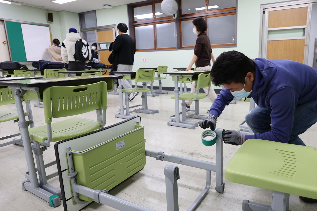 대학수학능력시험을 이틀 앞둔 15일 오후 서울 영등포구 선유고등학교에서 선생님과 학생들이 잡음이 나는 책걸상을 손보고, TV 모니터와 게시판 등을 흰 종이로 가리는 등 시험장 준비를 하고 있다. [연합]