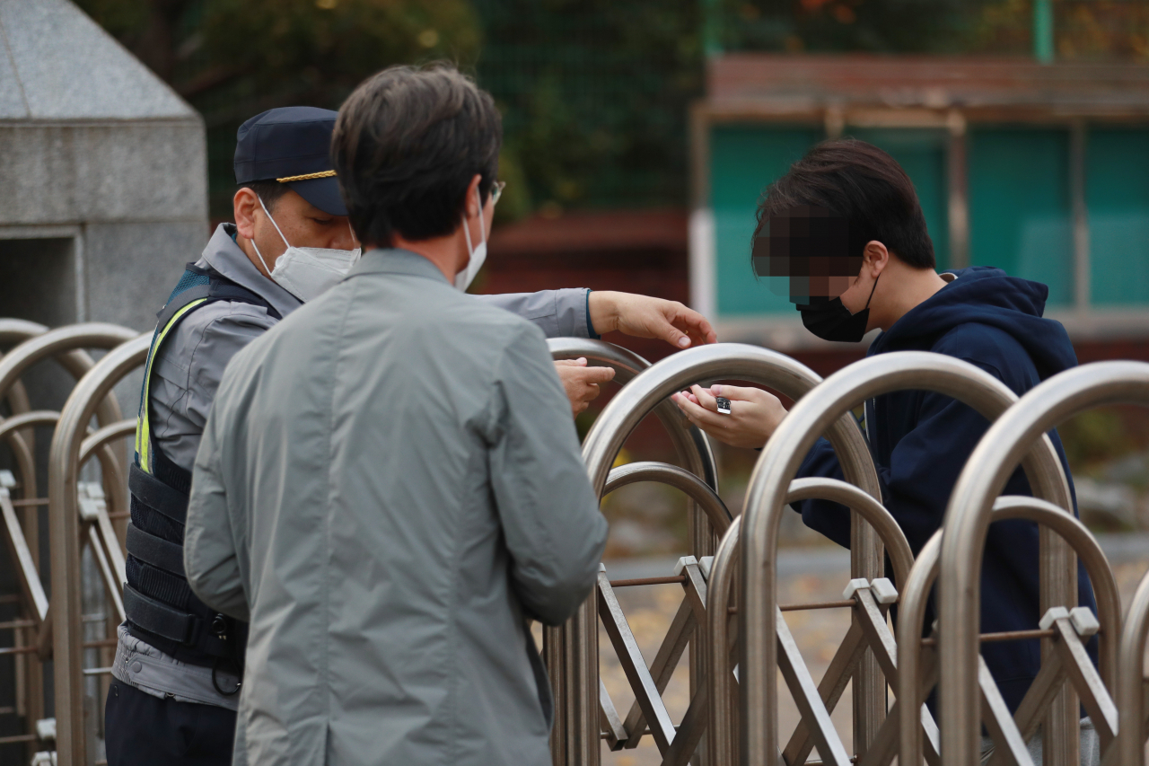 2023학년도 대학수학능력시험(수능)일인 17일 오전 시험장이 마련된 부산 해운대구 부흥고등학교에서 재송지구대 한순성 경위가 시계를 두고 온 한 수험생에게 자신의 손목시계를 빌려주고 있다. [연합]