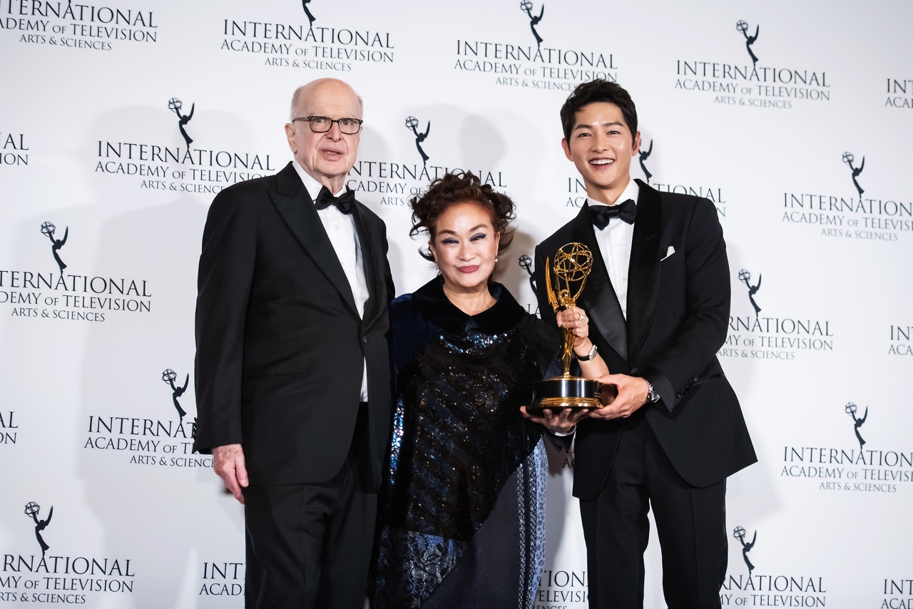 이미경 CJ 부회장이 미국 뉴욕에서 열린 국제 에미상 시상식에서 브루스 파이스너(Bruce L. Paisner) IATAS 회장과 시상자로 참석한 배우 송중기와 함께 기념촬영을 하고 있다. [CJ ENM 제공]