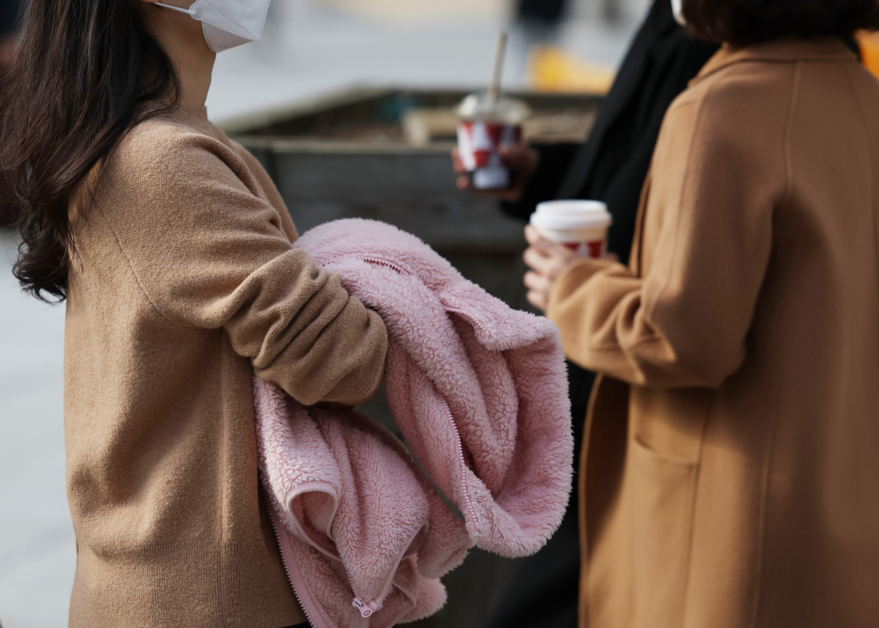 큰 추위 없는 늦가을 날씨가 이어지고 있는 21일 오후 겉옷을 손에 든 시민들이 광화문네거리를 지나고 있다. [연합]