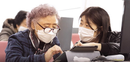 시니어 디지털 리터러시 교육 봉사자가 어르신에게 디지털기기 사용법을 설명하고 있다.[CJ올리브네트웍스 제공]