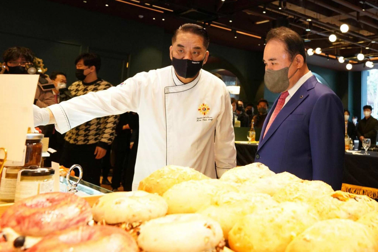제너시스BBQ 그룹 윤홍근 회장(오른쪽)이 직원으로부터 제품에 대한 설명을 듣고있다. [BBQ치킨 제공]