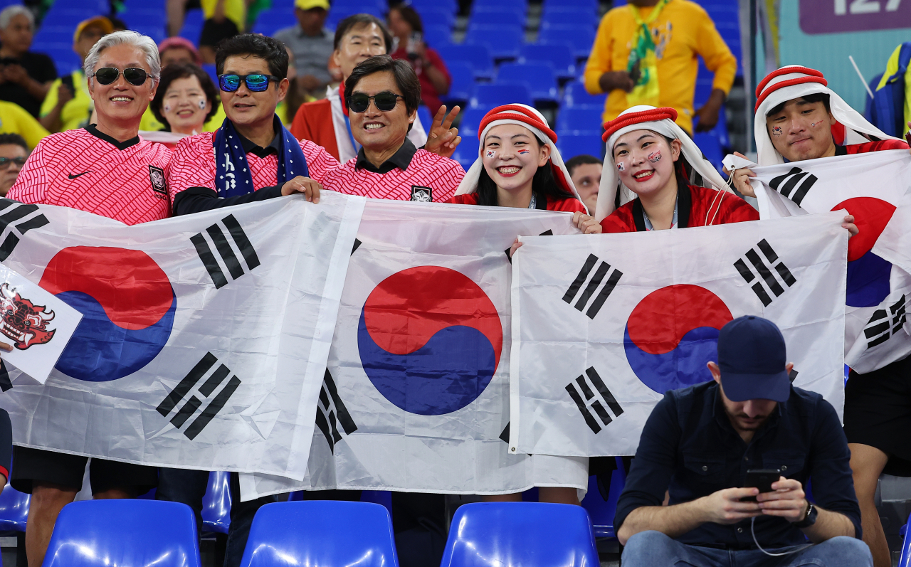6일(한국시간) 카타르 도하 974스타디움에서 열린 2022 카타르 월드컵 16강전 대한민국과 브라질의 경기를 찾은 축구팬들이 태극기를 들고 포즈를 취하고 있다. [연합]