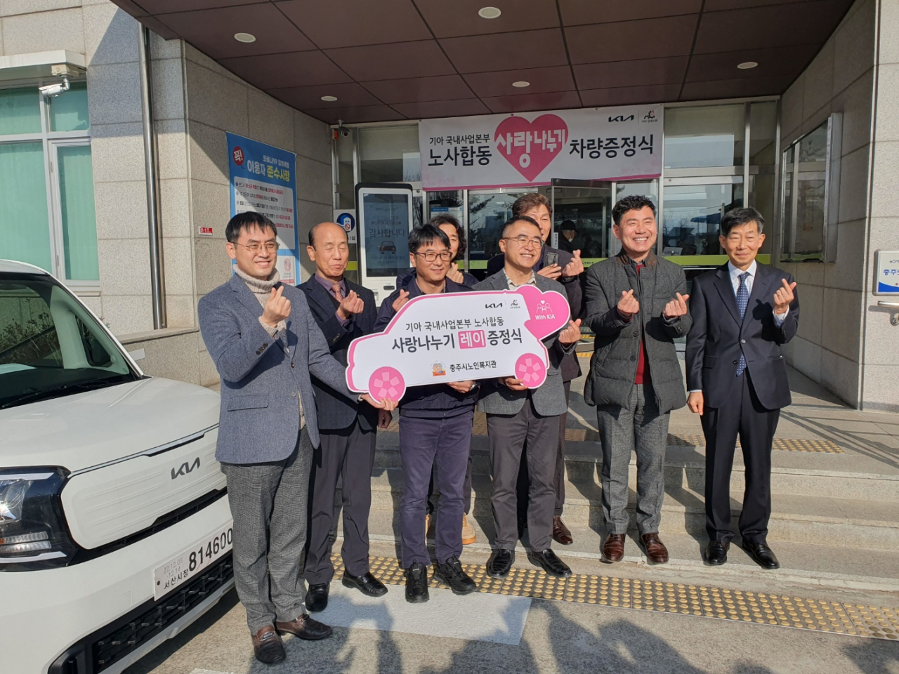 12일 충주시노인복지관에서 열린 사랑나누기 차량 기증식에서 최종웅 기아 국내사업본부 판매지원실장, 최정현 판매지회장이 레이를 전달한 뒤 기념사진을 촬영하고 있다. [기아 제공]