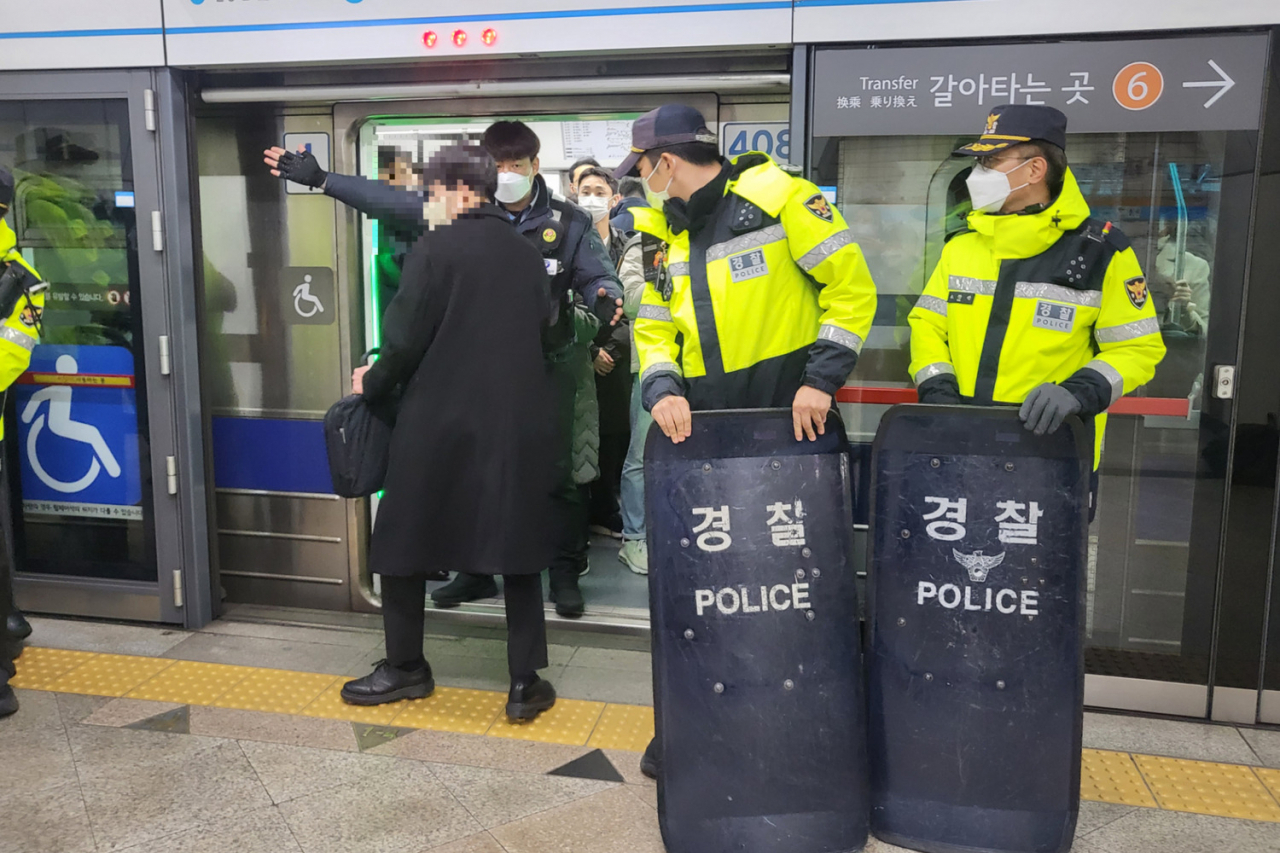 13일 전국장애인차별철폐연대가 247일째 선전전을 진행하는 동안 서울교통공사 관계자가 시민에게 뒤편 열차에 탑승할 것을 안내하고 있다. [박지영 기자/park.jiyeong@]