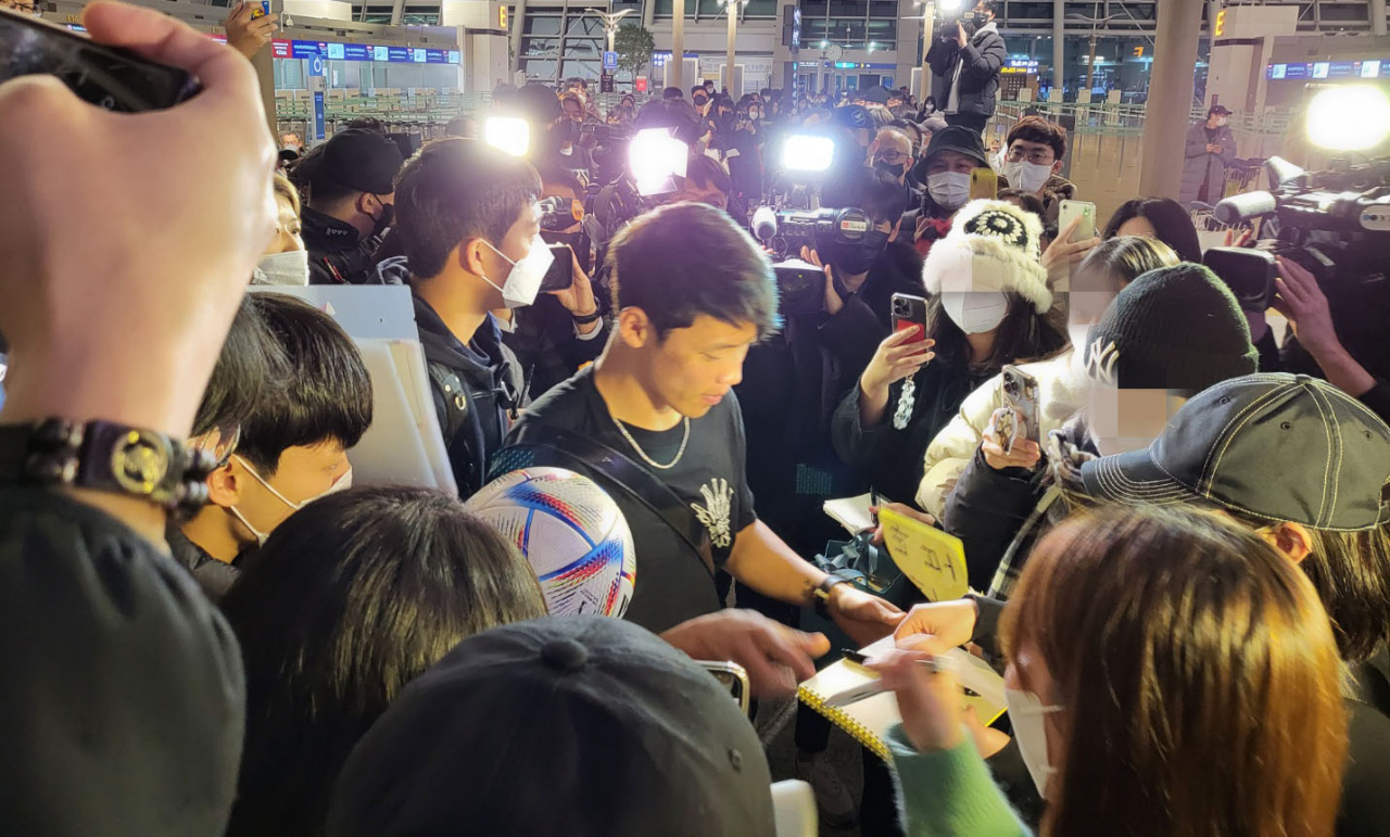 황희찬이 10일 인천국제공항에서 검정색 패딩을 벗고 반팔 차림으로 팬들에게 사인을 해주고 있다. [연합]