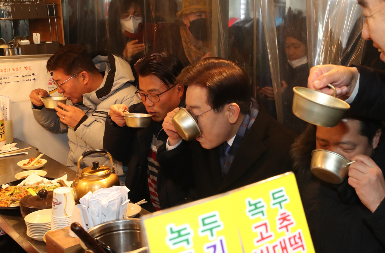 이재명 더불어민주당 대표가 13일 충남 천안시 동남구 천안중앙시장을 찾아 더불어민주당 관계자들과 막걸리를 마시고 있다. [연합]