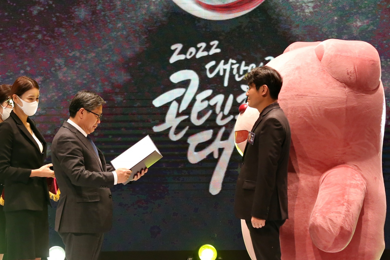‘2022년 대한민국 콘텐츠 대상’ 시상식에서 대통령상을 수상한 롯데홈쇼핑 자체 캐릭터 벨리곰. 왼쪽 두 번째부터 전병극 문화체육관광부 차관, 이보현 롯데홈쇼핑 미디어사업부문장. [롯데홈쇼핑 제공]