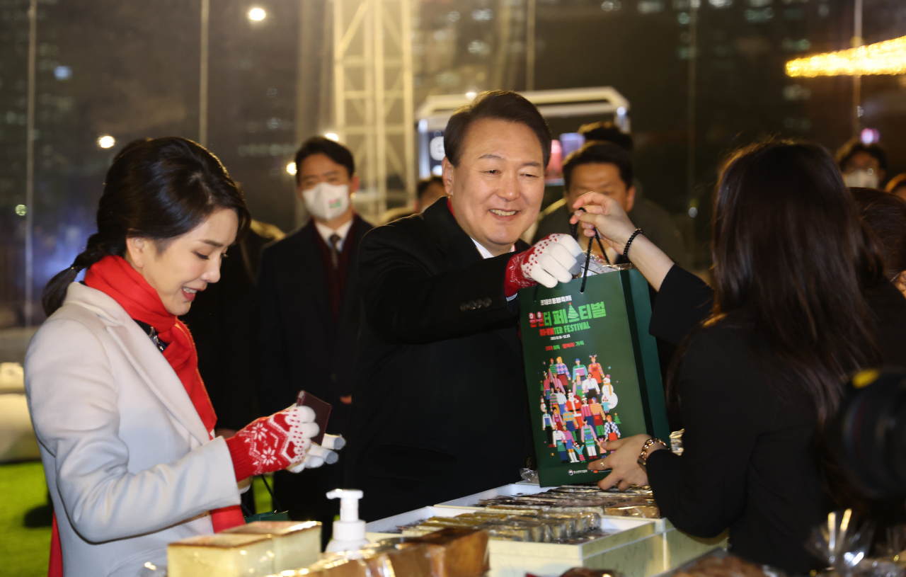 윤석열 대통령과 김건희 여사가 16일 오후 서울 종로구 열린송현광장에서 열린 윈·윈터 페스티벌 개막식에서 에어돔 부스를 방문, 물건을 구입하고 있다. [연합]