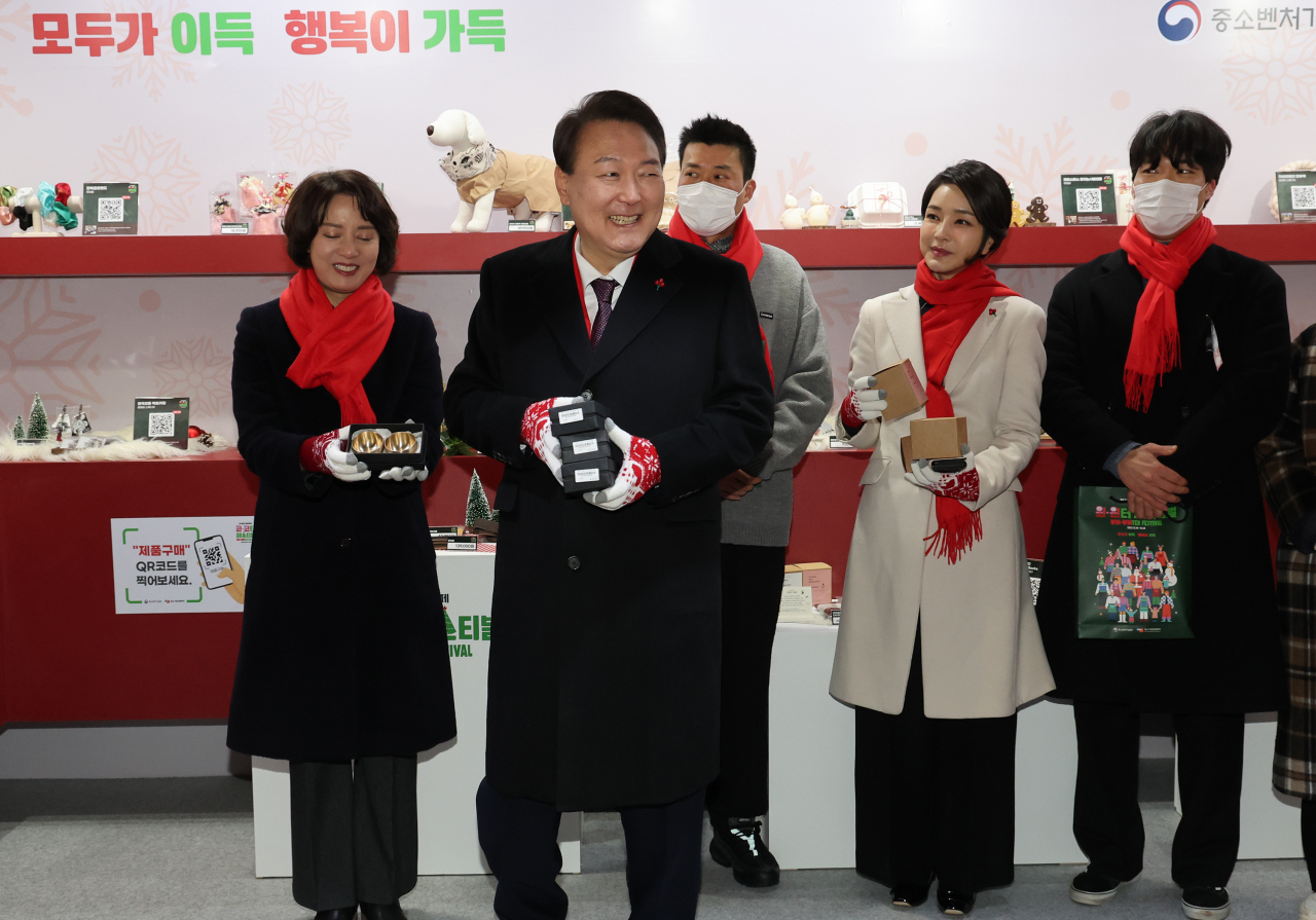 윤석열 대통령과 김건희 여사가 16일 오후 서울 종로구 열린송현광장에서 열린 윈·윈터 페스티벌 개막식에서 판매 부스를 방문해 물건을 구입하고 있다. [연합]