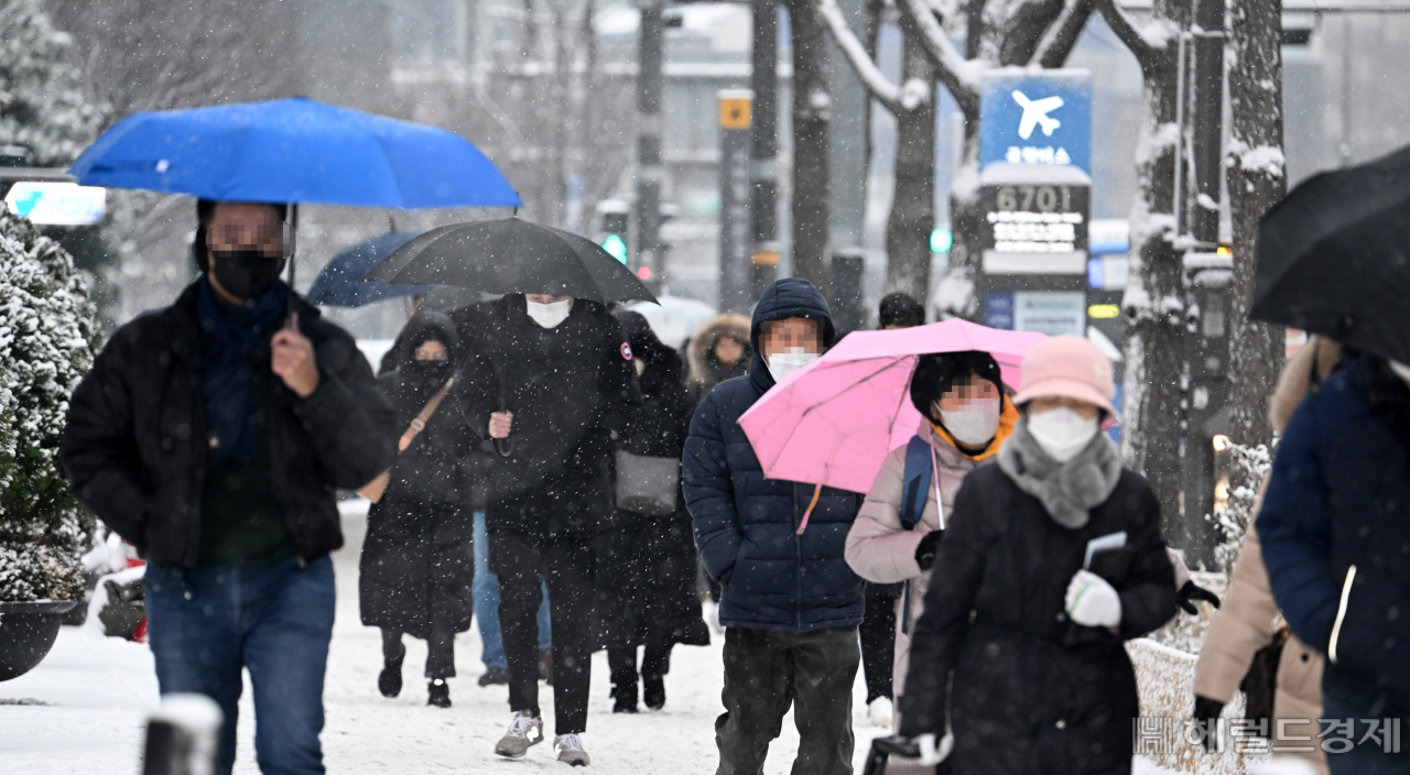 수도권과 중부지방에 대설주의보가 발효된 21일 서울 중구 프레스센터 인근에서 시민들이 내리는 눈을 맞으며 거리를 지나고 있다. 임세준 기자