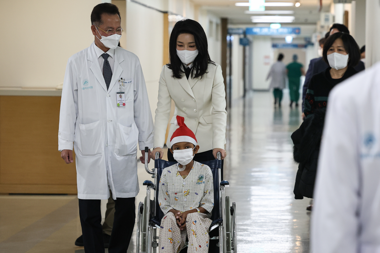 김건희 여사가 21일 서울 송파구 서울아산병원에서 심장질환 수술을 받고 회복 중인 캄보디아 아동 옥 로타군을 만나 의료진과 함께 이동하고 있다. [연합]