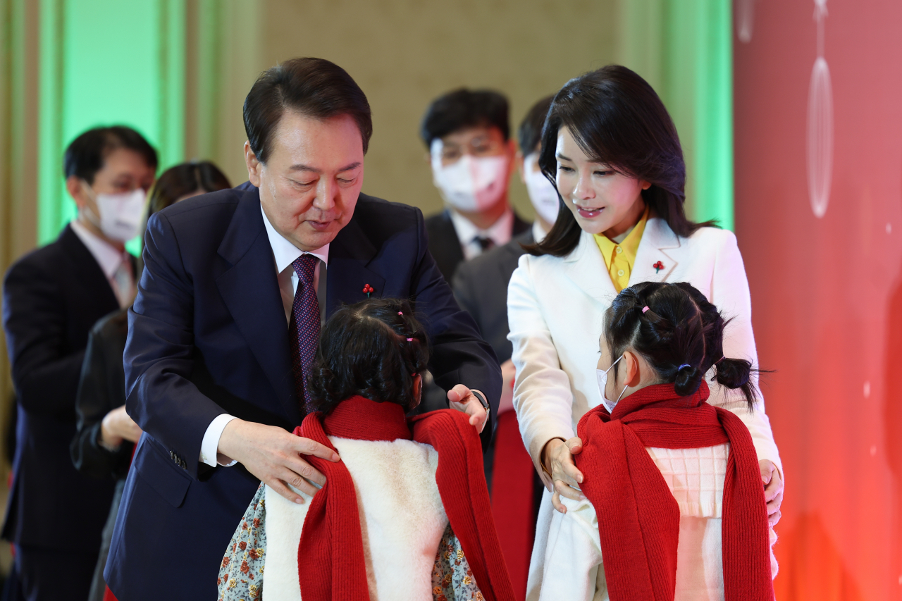 윤석열 대통령과 김건희 여사가 23일 청와대 영빈관에서 열린 보호아동·자립준비청년과 함께하는 크리스마스 행사에서 아이들에게 목도리를 걸어주고 있다. [연합]