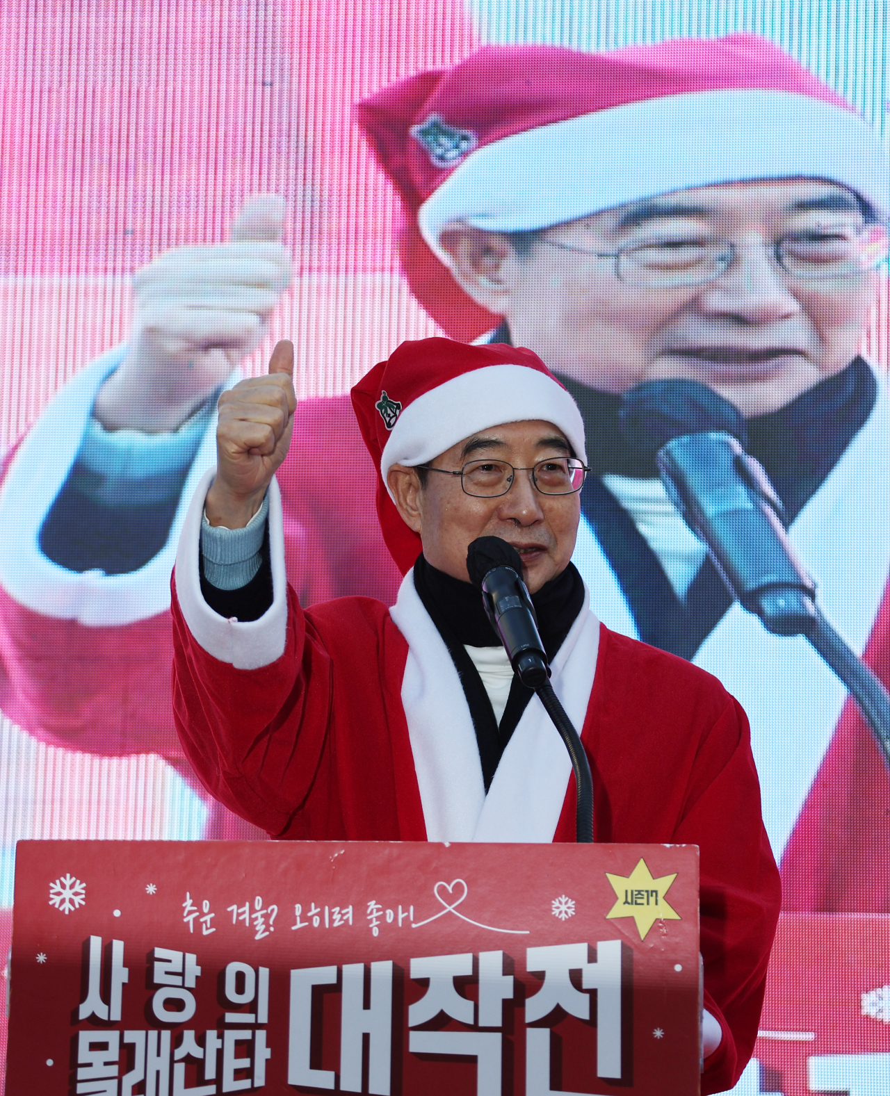한덕수 국무총리가 크리스마스이브인 24일 서울 서대문구 창천문화공원에서 소외계층에 선물을 전달할 산타 분장을 한 자원봉사자들과 함께 선물 배송을 위해 출발 전 성탄을 축하하는 '사랑의 몰래산타 대작전' 출정식 행사에 참가해 축사를 하고 있다. [연합]