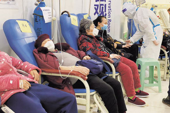 지난 23일(현지시간) 중국 남서부 충칭시 충칭의과대학 제2부속병원에서 코로나19 환자들이 팔에 주사를 꽂은 채 줄지어 앉아있다. [연합]