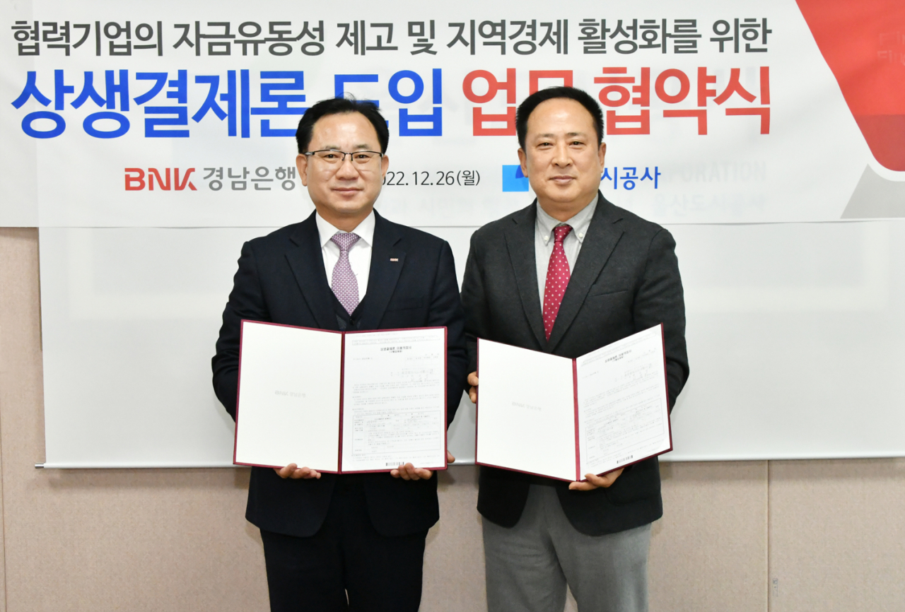 BNK경남은행 이상봉 상무(사진 왼쪽)와 울산도시공사 고호근 본부장이 ‘상생결제론 도입 업무 협약’을 체결하고 있다. [BNK경남은행 제공]