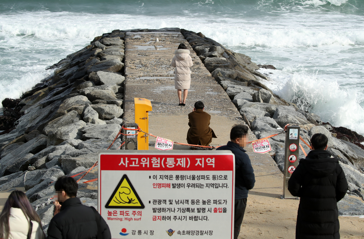26일 일부 관광객들이 너울성 파도로 풍랑특보가 발효되면서 출입이 금지된 유명 드라마 촬영지 강원 강릉시 주문진 방사제에서 다소 위험한 기념사진을 찍고 있다. [연합]