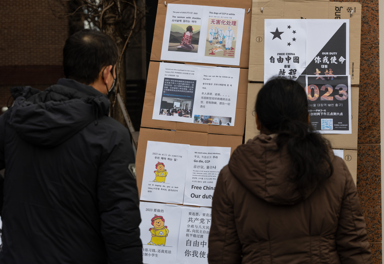 31일 오후 서울 영등포구 대림역 인근에서 재한국제인권연대가 주최한 중국 코로나19 봉쇄 정책 반대 집회에 걸린 유인물들을 한국에 거주중인 중국인들이 읽고 있다. [연합]