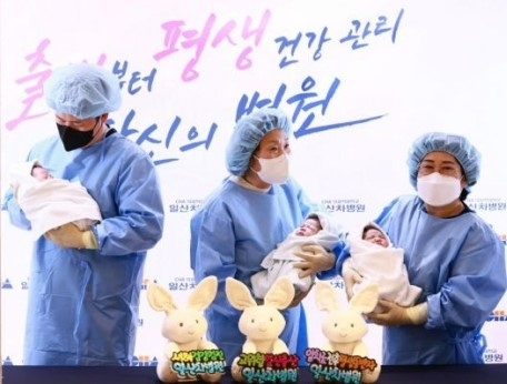 2023년 1월 1일 0시에 태어난 복동이(태명·여아)와 남녀 쌍둥이 짱짱이, 짱순이를 가족들이 안고 기념 촬영을 하고 있다.[일산 차병원 제공]