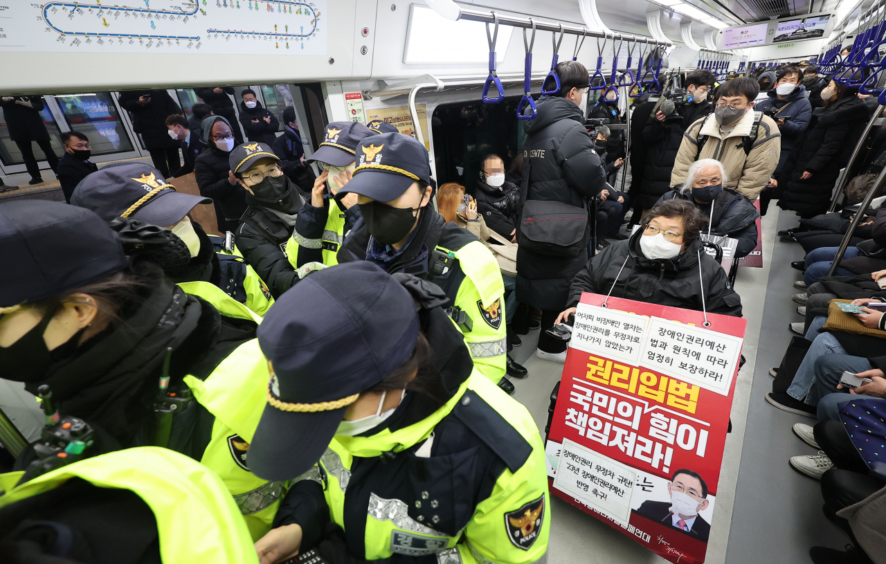 전국장애인차별철폐연대 회원들이 지난해 12월 19일 오전 서울 지하철 1호선 용산역에서 지난 14일 지하철 탑승 시위 중 무정차 통과 조치에 규탄하며 기습시위를 하고 있다. [연합]