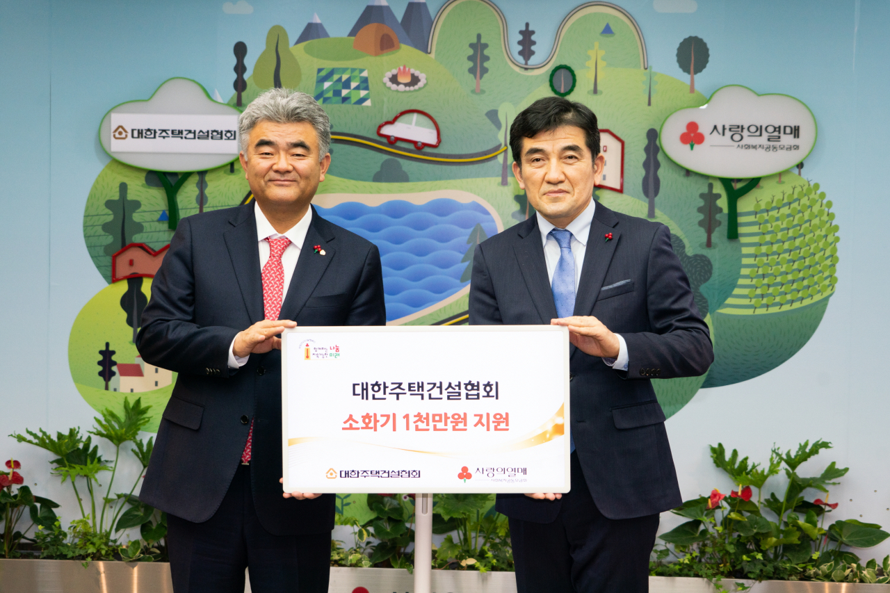 정원주 대한주택건설협회 회장(사진 왼쪽)이 사랑의 열매 황인식사무총장에게 ‘소화기 기증서’를 전달하고 있다.