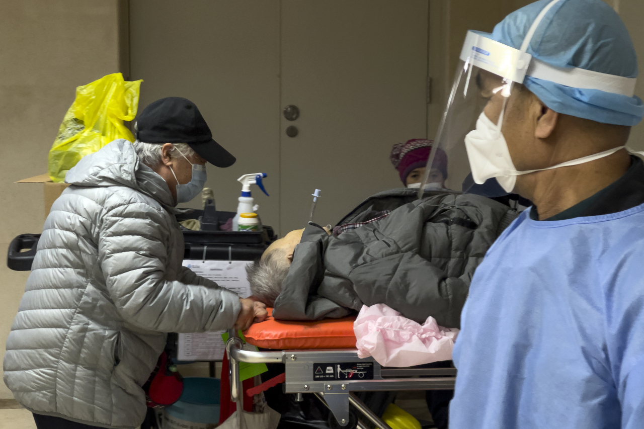 중국 베이징의 한 병원에서 의료진이 노인 환자를 바라보고 있다. [AP]