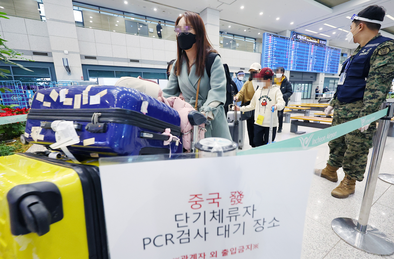 지난 8일 오후 인천국제공항 제1여객티미널을 통해 입국한 중국발 입국자들이 검역지원단의 안내를 받아 PCR 검사센터로 향하고 있다. [연합]