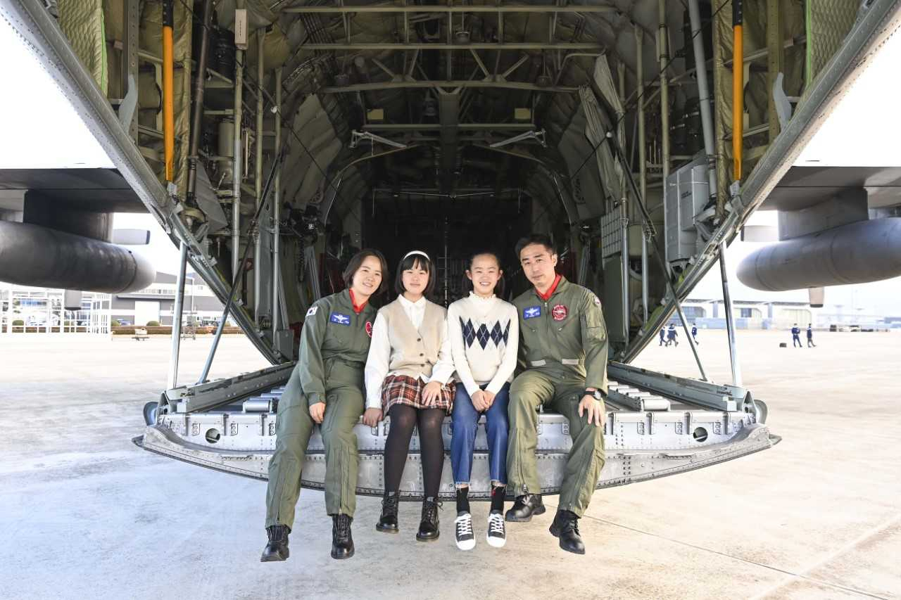 공군 최초 비행대대장 부부인 김익규, 김민지 중령이 쌍둥이 자매 김영설·은설 양과 C-130 수송기 램프 도어에 앉아 사진을 촬영하고 있다. 사진 왼쪽부터 김민지 중령, 은설·영설 양, 김익규 중령. [공군 제공]