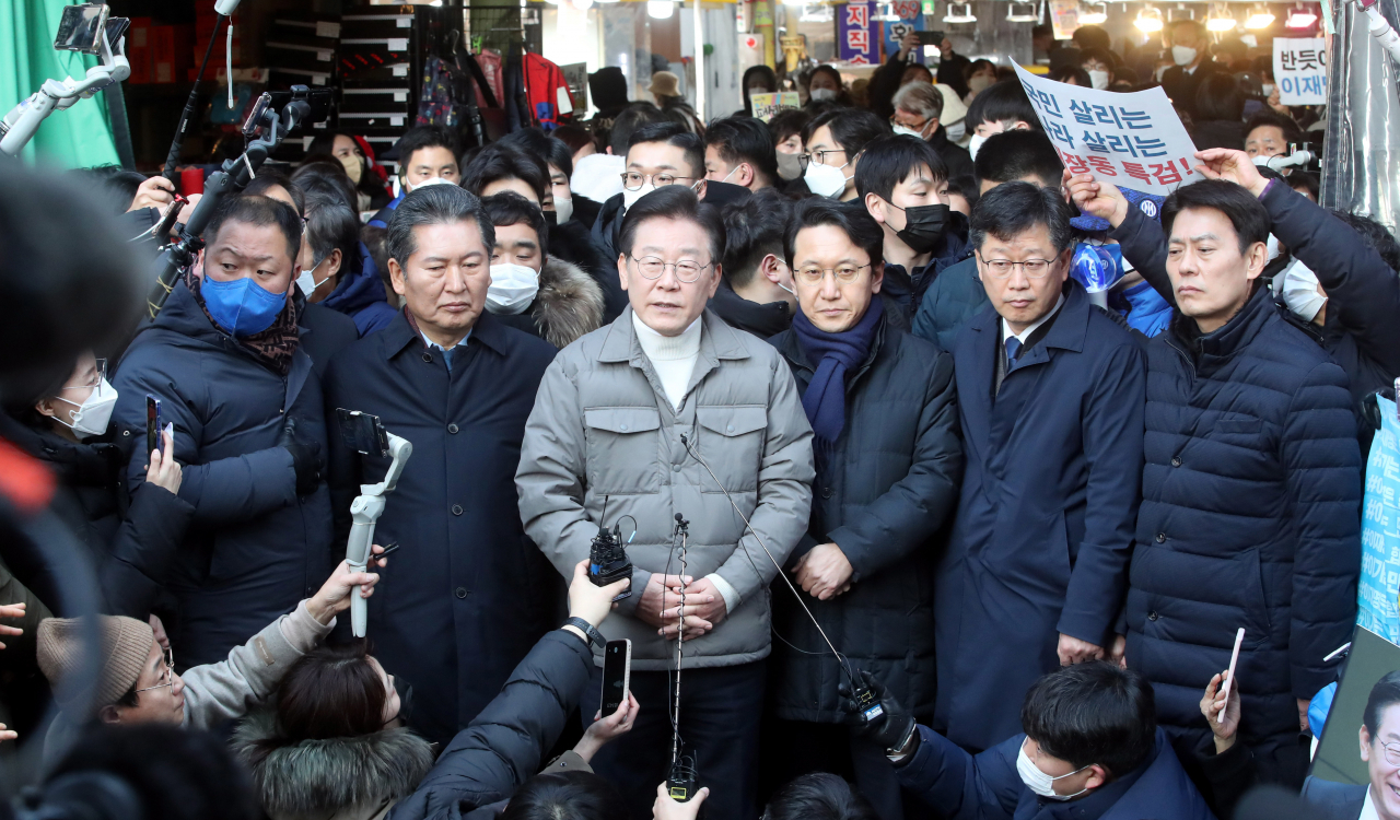 이재명 더불어민주당 대표(가운데)가 설 명절을 앞두고 18일 오후 서울시 마포구 망원시장을 방문해 취재진의 질문에 답변하는 모습. [연합]