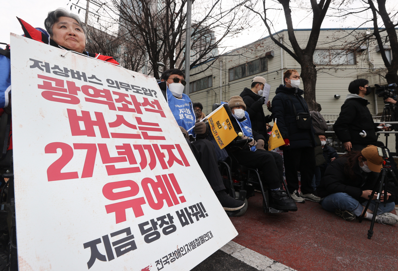 전국장애인차별철폐연대(전장연) 회원이 19일 오후 서울 서초구 남부터미널 앞에서 열린 시외버스 이동권 촉구 집회에서 팻말을 들고 있다. [연합]