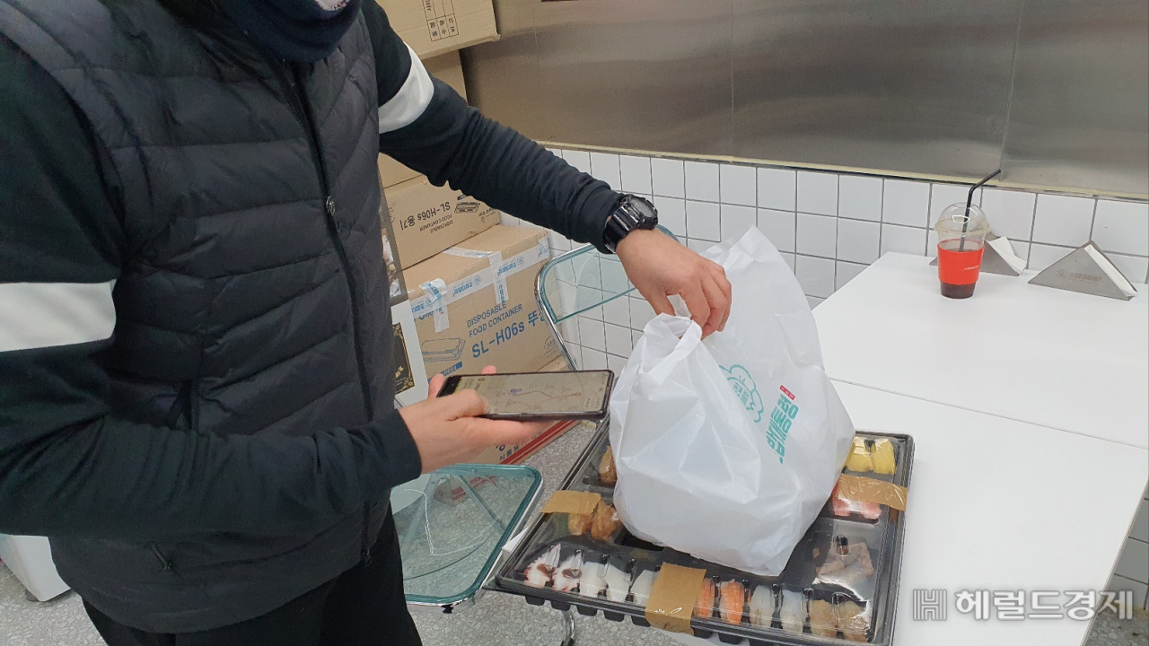 배달전문점에서 초밥세트를 전달받아 배달을 준비중이다.