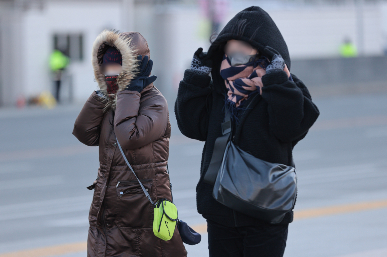 서울 최저기온이 영하 15도 이하로 떨어지며 강추위가 찾아온 24일 오전 서울 종로구 광화문광장에서 시민들이 외투 모자를 쓰고 있다. [연합]