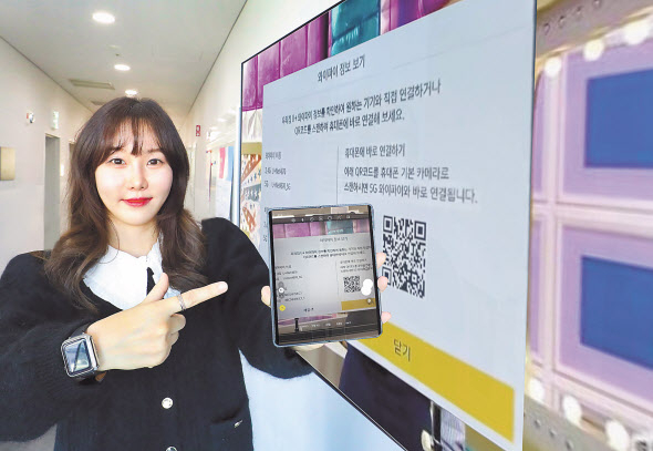 LG유플러스는 업계 최초로 U+tv에 QR코드 와이파이(WiFi) 접속 기능을 적용했다. 사진은 LG유플러스 직원이 U+tv 속 QR코드를 스마트폰 카메라로 촬영해 와이파이를 연결하는 모습. [LG유플러스 제공]
