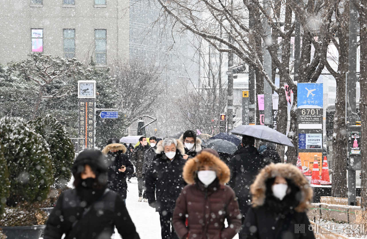 수도권 일대에 대설주의보가 발효된 26일 서울 종로구 광화문사거리 일대에 시민들이 내리는 눈을 맞으며 거리를 지나고 있다. 임세준 기자