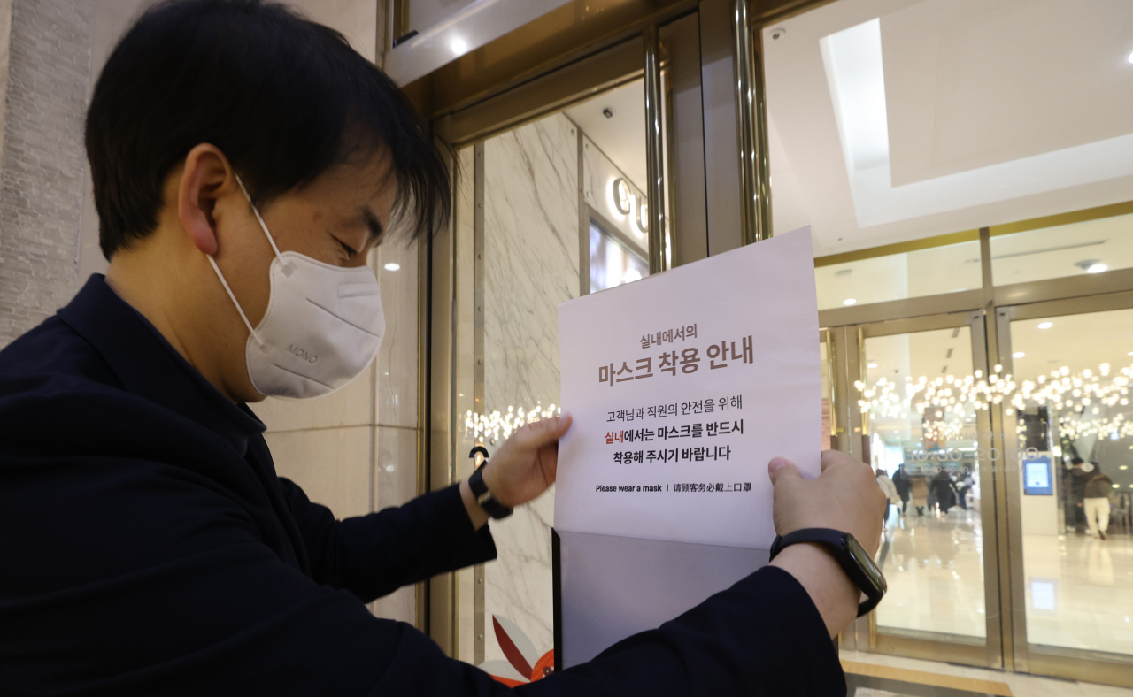 실내마스크 착용 의무 해제를 하루 앞둔 29일 오후 서울 시내 한 백화점에서 관계자가 마스크 착용 안내문을 철거하고 있다. 오는 30일부터 마스크 착용 의무 조치가 '권고'로 전환된다. 다만 의료기관과 약국, 감염취약시설, 대중교통 등에서는 실내 마스크 착용 의무가 유지된다. [연합]