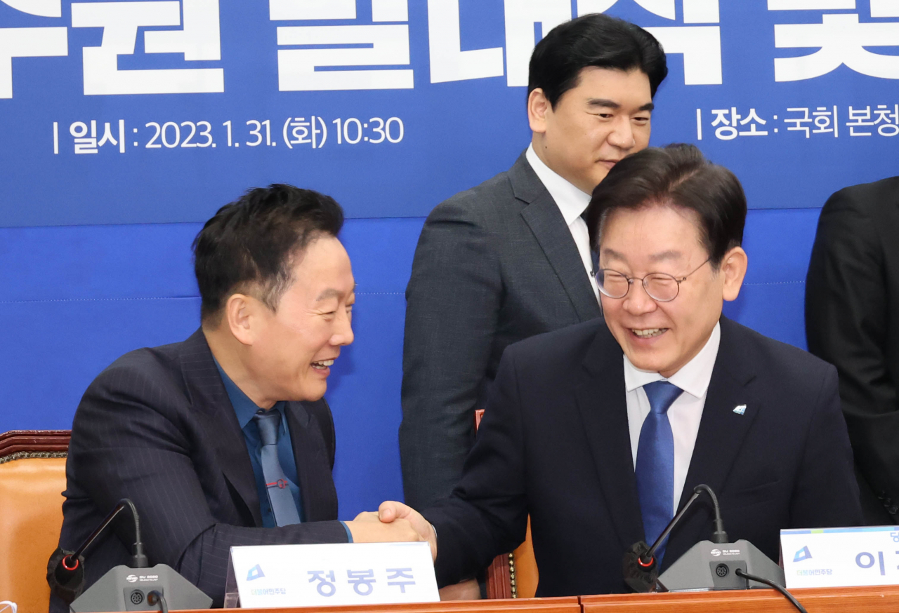 이재명 더불어민주당 대표가 31일 국회에서 열린 교육연수원 발대식에서 정봉주 교육연수원장과 악수하고 있다. [연합]