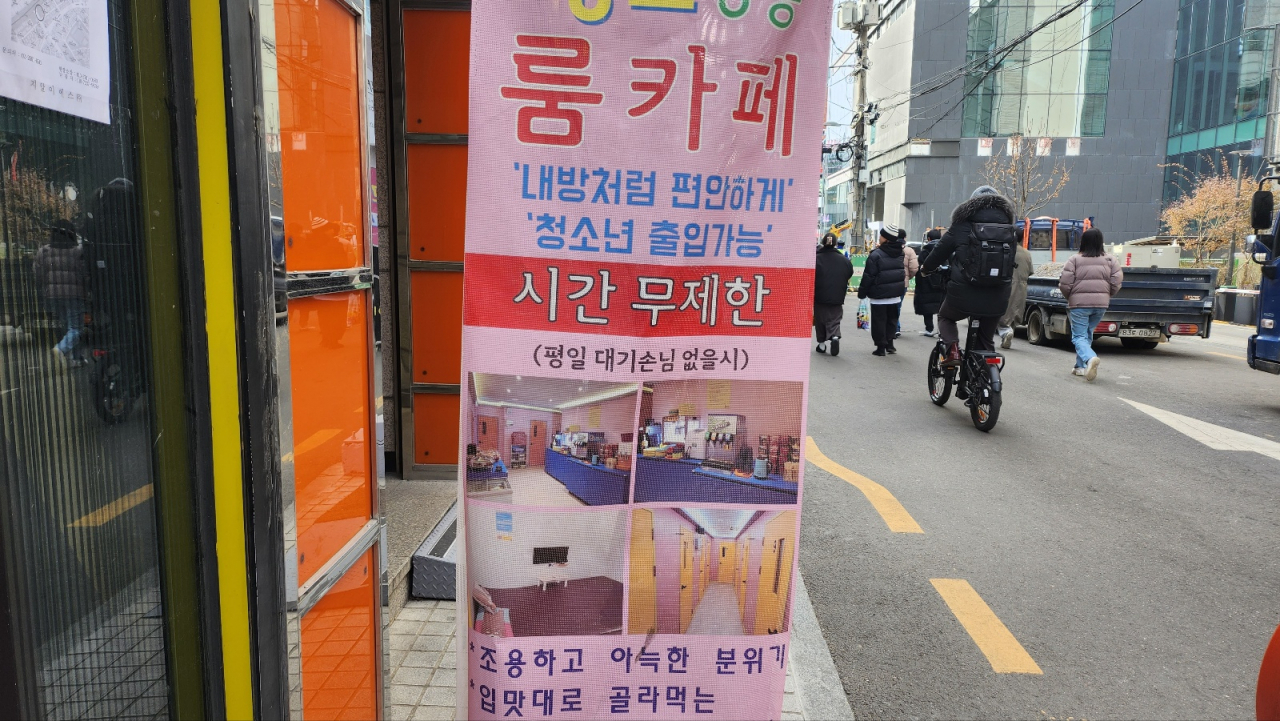 Pedestrians walk by a banner advertising a room cafe in Mapo-gu, Seoul, which mentions "Adolescents are allowed." (Lee Jung-youn/The Korea Herald)