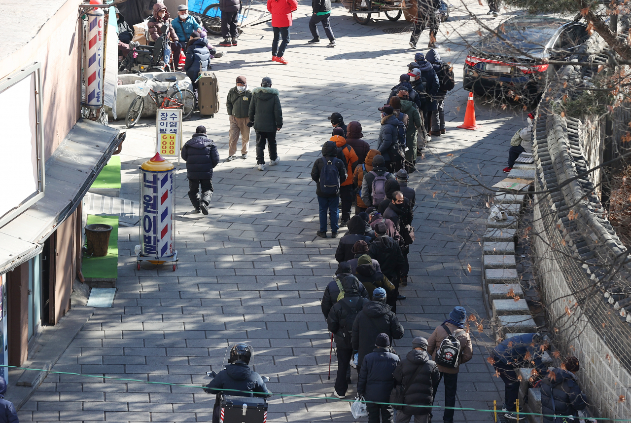 Elderly people line up in front of Wongaksa Pagoda in Jongno-gu, central Seoul, to receive free meals. (Yonhap)