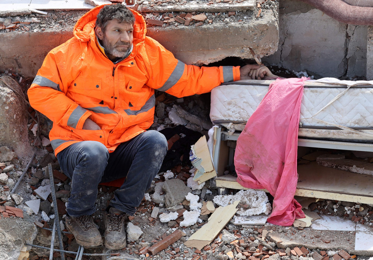 Mesut Hancer holds the hand of his 15-year-old daughter Irmak, who died in the earthquake in Kahramanmaras, close to the quake's epicentre, the day after a 7.8-magnitude earthquake struck the country's southeast, on Tuesday (AP)