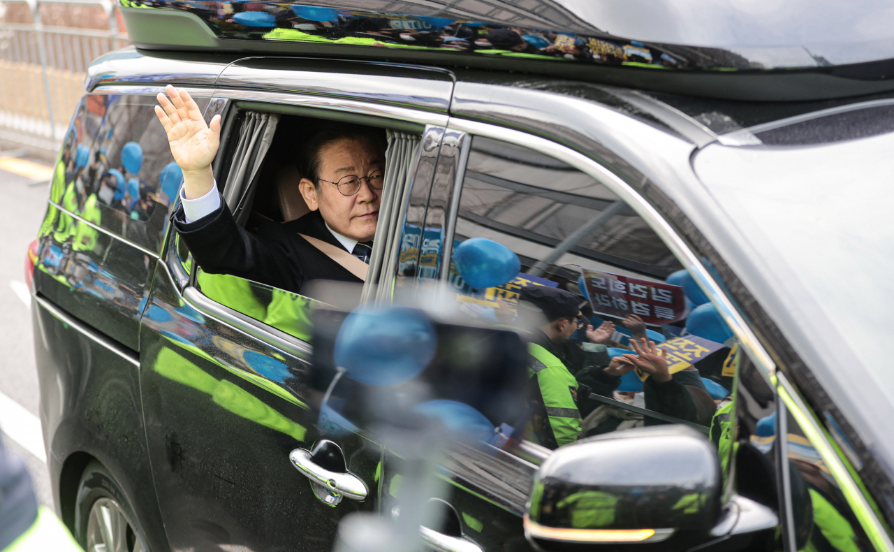 Democratic Party of Korea leader Rep. Lee Jae-myung drives past and waves to supporters on his way to Seoul prosecutors’ office on Friday. Many in the crowd wave blue balloons to express support of the Democratic Party. (Yonhap)