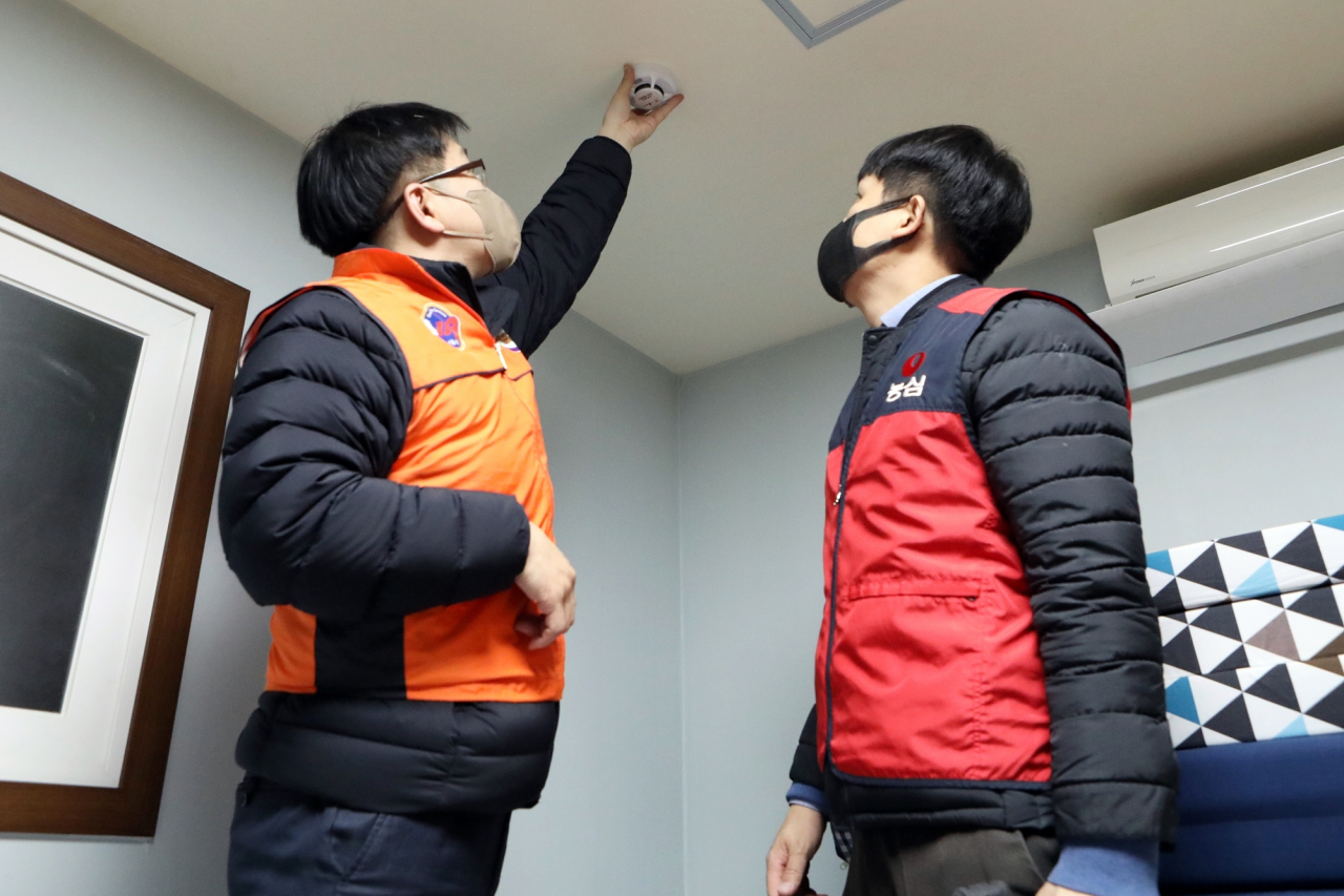 농심 직원(오른쪽)과 소방대원이 화재경보기를 설치하는 모습. [농심 제공]