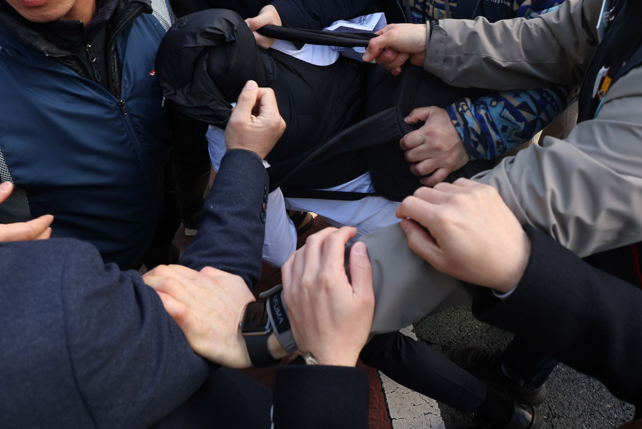 민주노총 경남지역본부 조합원이 23일 오전 경남 창원시 성산구 본부 입구에서 국정원 수사관에게 신분을 요청하고 있다. 해당 수사관은 기자회견이 진행되는 동안 촬영을 시도했고, 조합원에게 최초 '기자'라고 속였다가 뒤늦게 국정원 직원임이 확인됐다. [연합]
