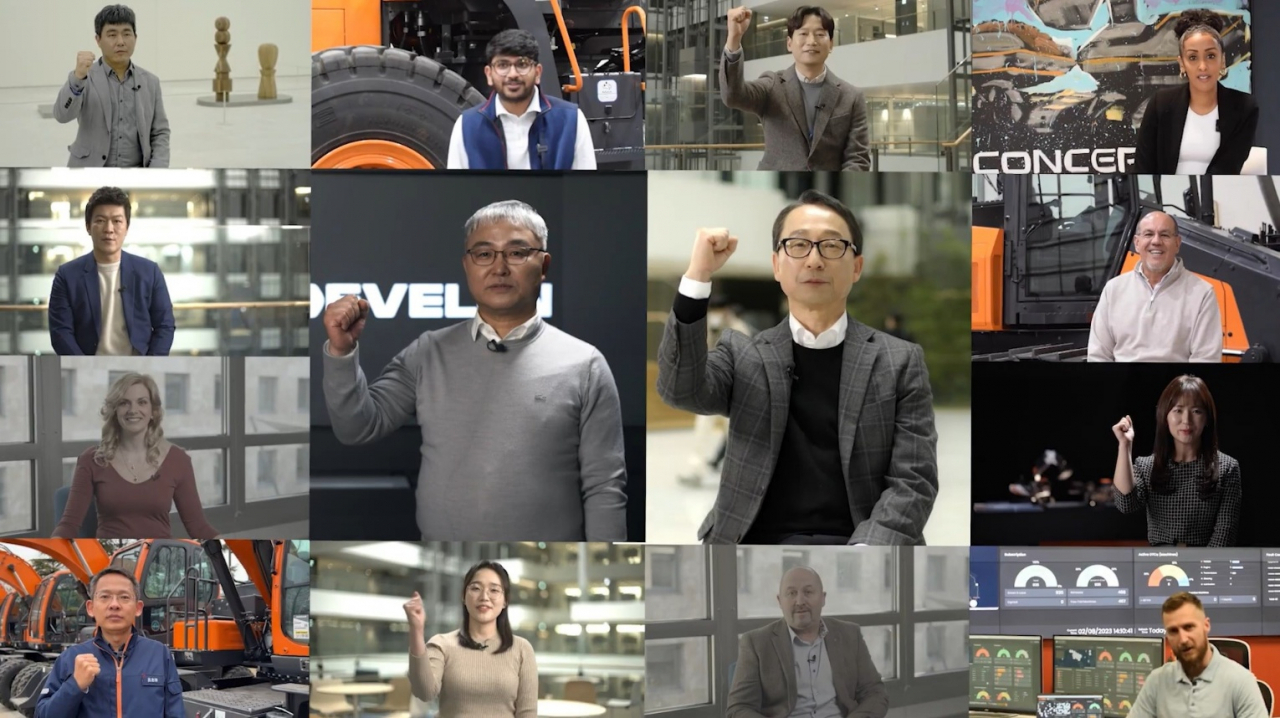 현대두산인프라코어가 27일 공개한 새 브랜드 ‘디벨론’(DEVELON) 쇼케이스 영상의 한 장면. 조영철(가운데 오른쪽) 현대두산인프라코어 사장과 오승현(가운데 왼쪽) 현대두산인프라코어 대표, 글로벌 직원 12명이 “위 아 디벨론(We are Devolon)”을 외치고 있다. [현대두산인프라코어 유튜브]