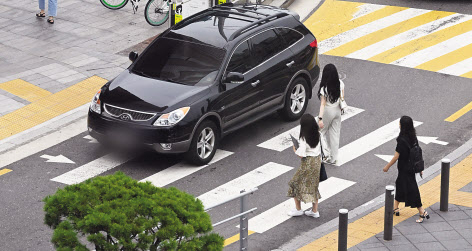 지난해 7월 서울 용산구의 한 교차로에서 시민들이 횡단보도를 건너는 도중 차량이 행인을 무시한 채 횡단보도를 지나고 있다(왼쪽). 임세준 기자