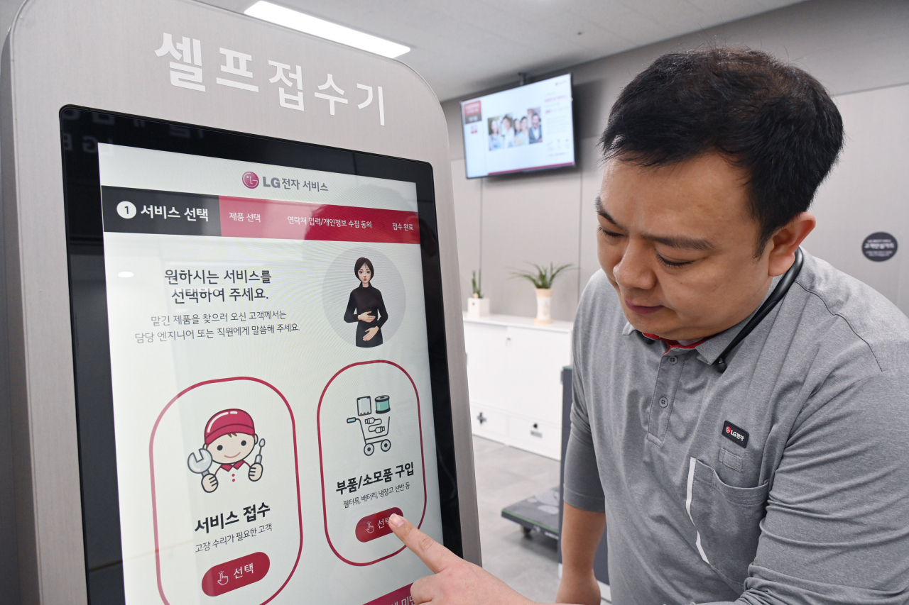 LG전자가 최근 전국 130여 개 서비스센터에 설치된 고객 접수용 키오스크에 독자 개발한 디지털휴먼 수어 서비스를 도입했다. LG전자 서비스엔지니어가 서울 광진구에 위치한 LG전자 광진서비스센터에 설치된 키오스크에서 디지털휴먼의 수어 안내를 받아 서비스를 접수하는 방법을 안내하고 있다. [LG전자 제공]